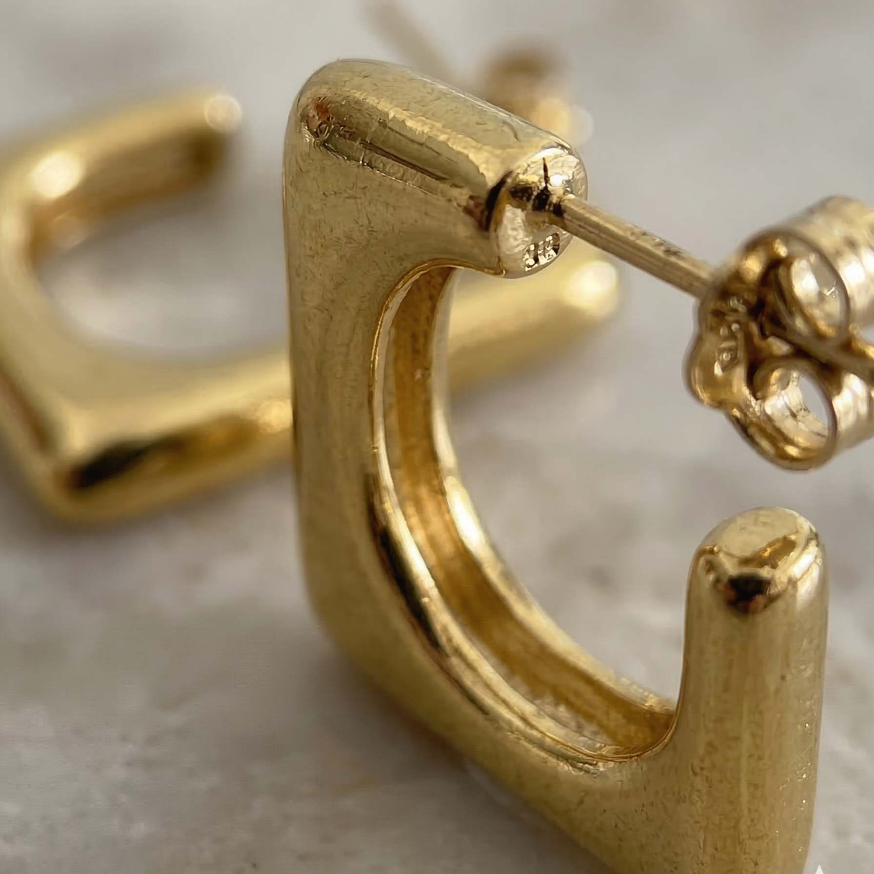 Gold hoop earrings on a neutral background