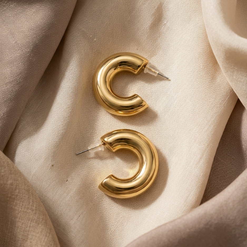 Gold hoop earrings on a beige fabric background