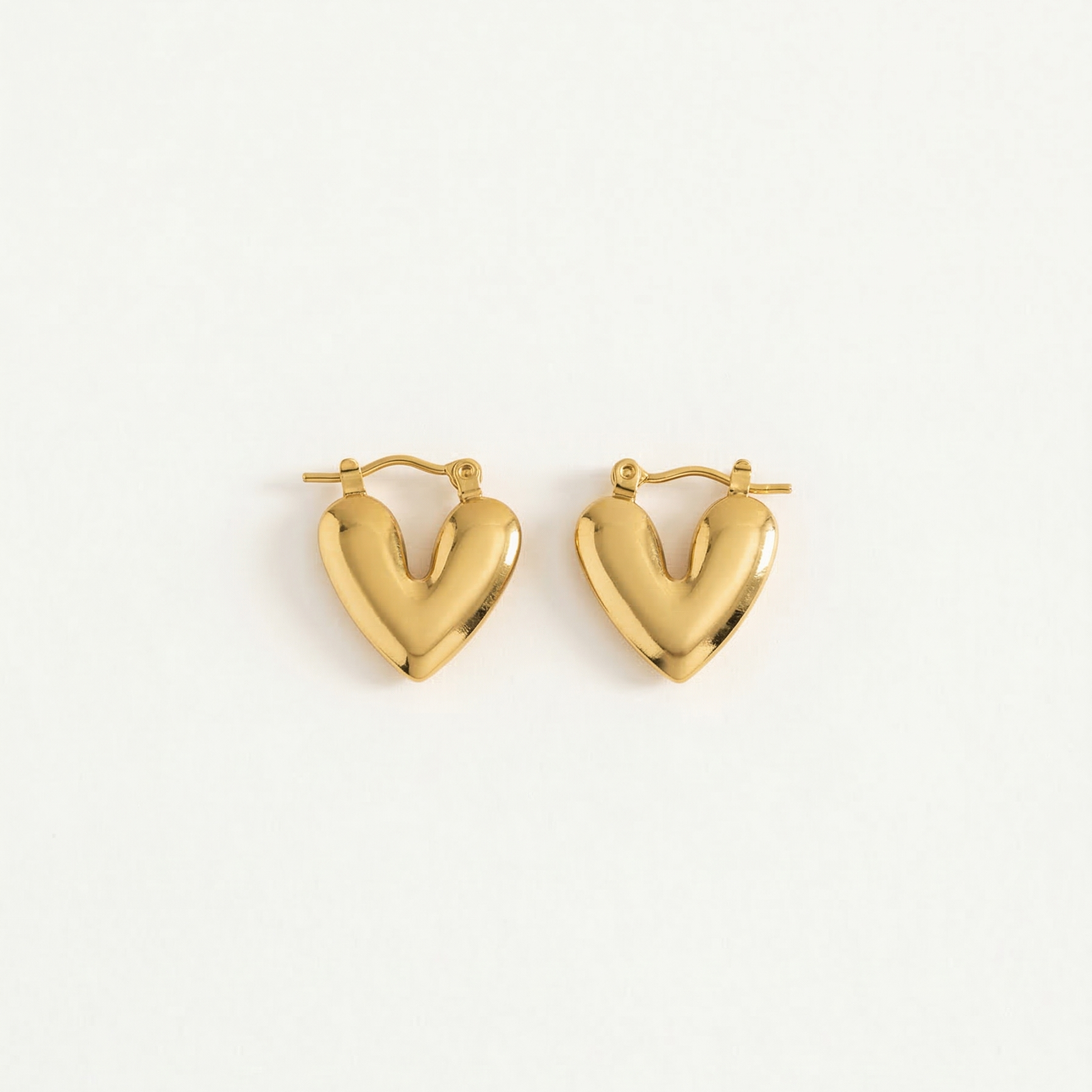 Gold heart-shaped earrings on a white background