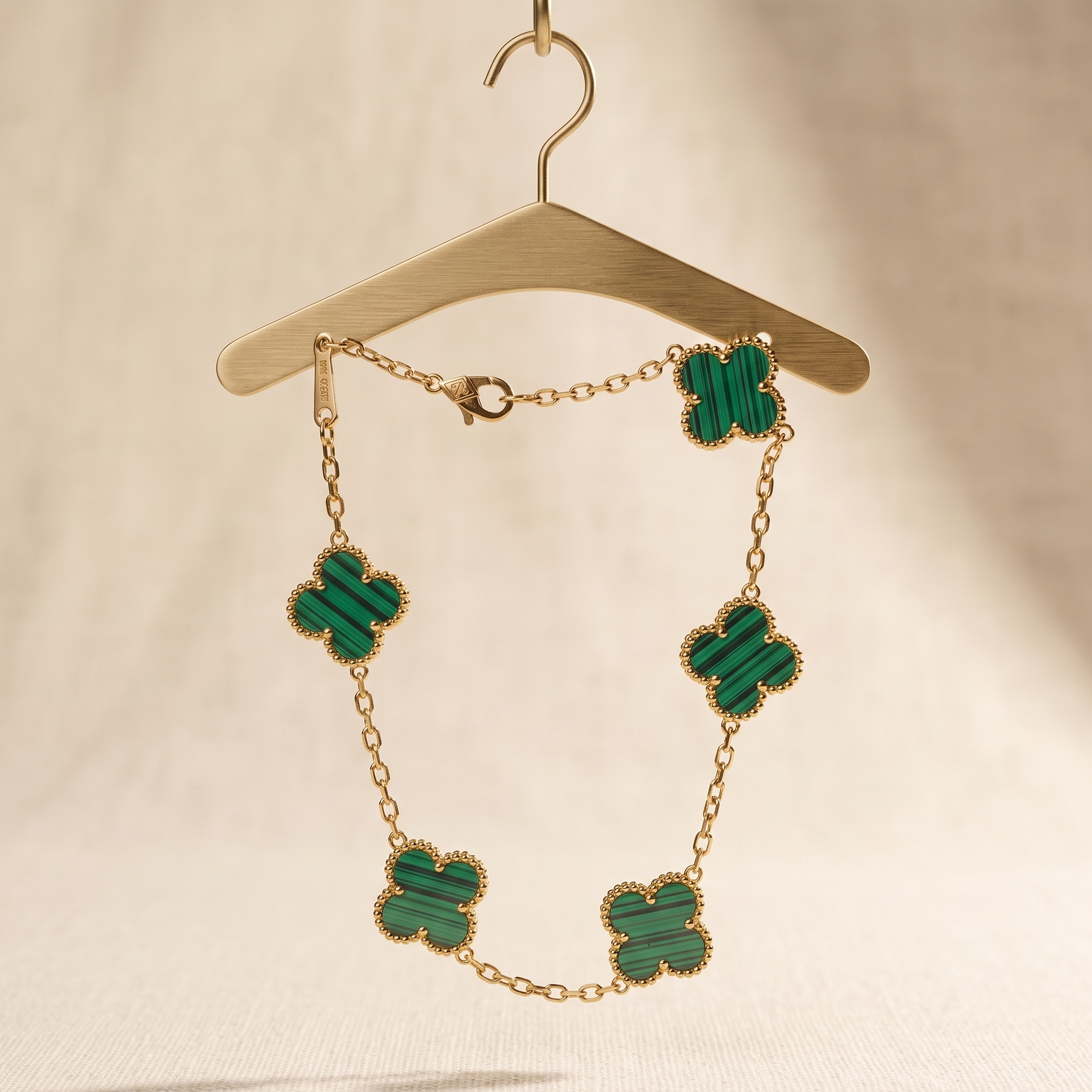 Gold necklace with green clover-shaped pendants on a beige background