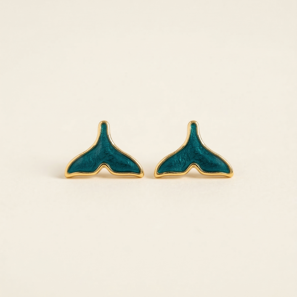 Teal and gold whale tail earrings on a beige background