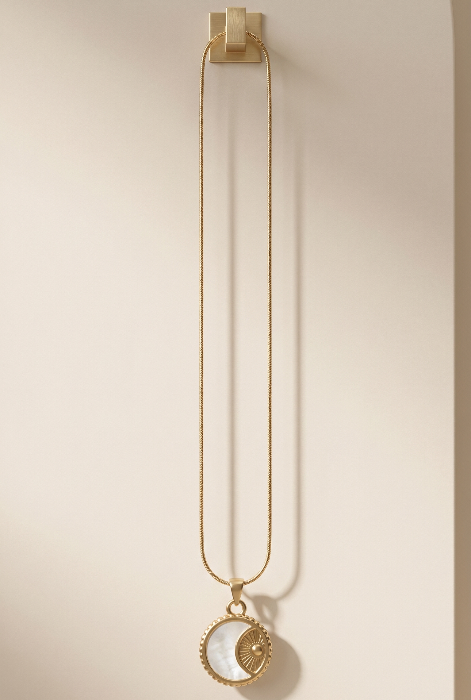 Gold necklace with a pendant on a beige background