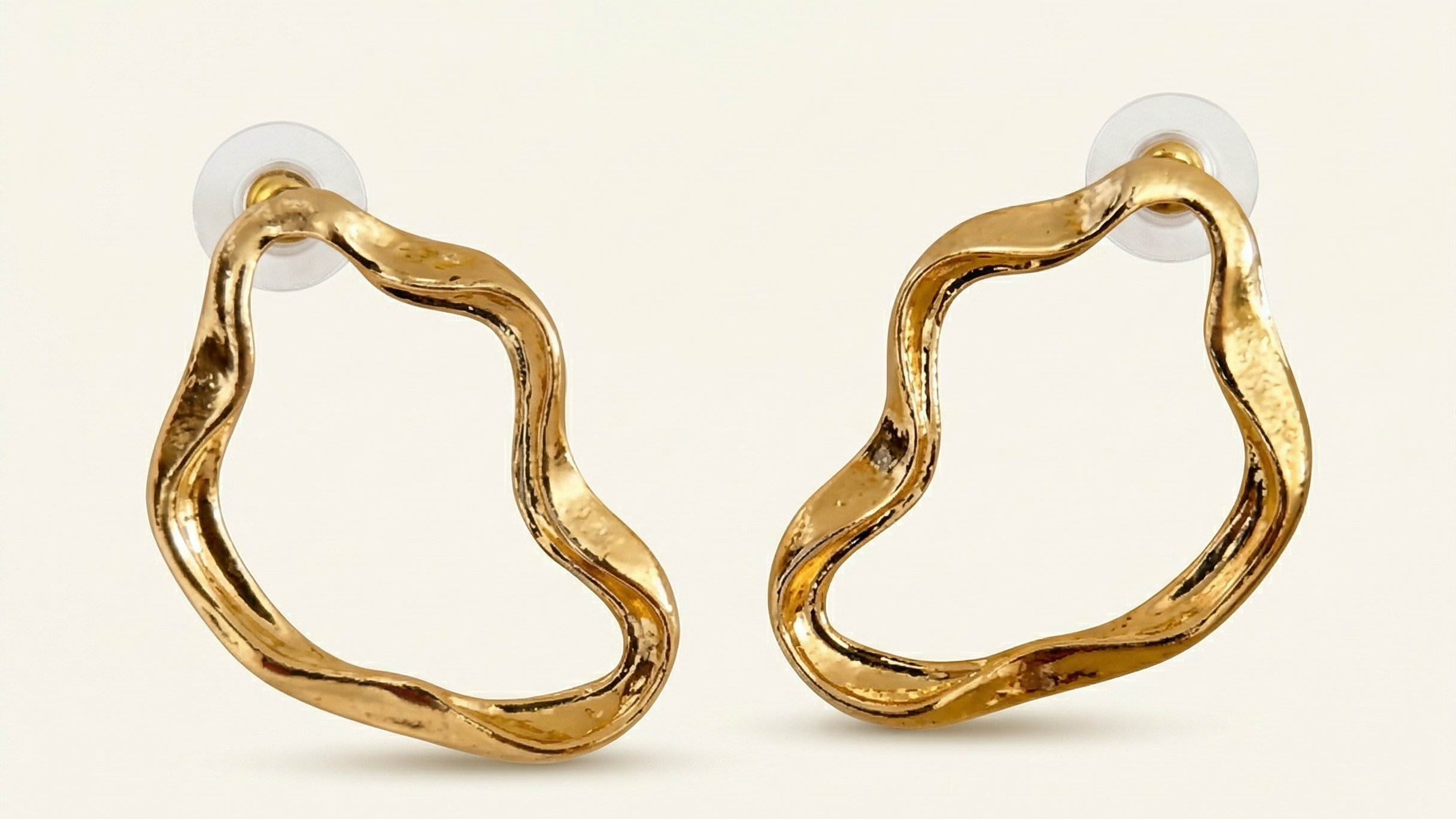 Gold hoop earrings on a light beige background