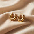 Gold hoop earrings on a beige fabric background