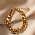 Gold chain bracelet on a beige fabric background