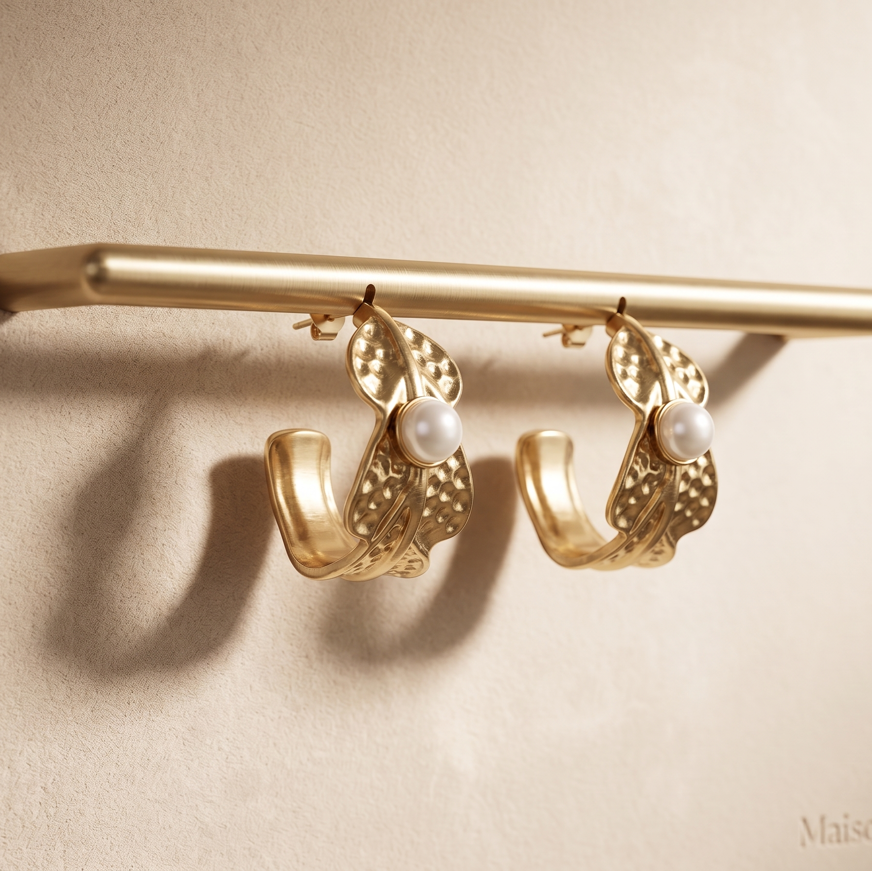 Gold hoop earrings with pearl centers on a beige background