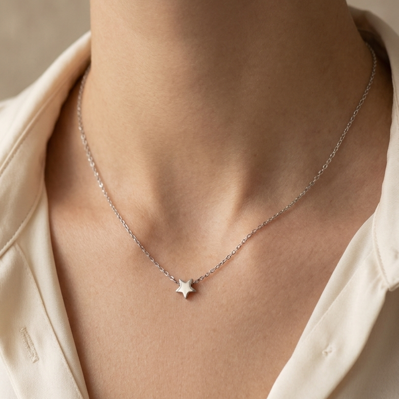 Necklace with a star pendant worn by a person in a light-colored shirt.