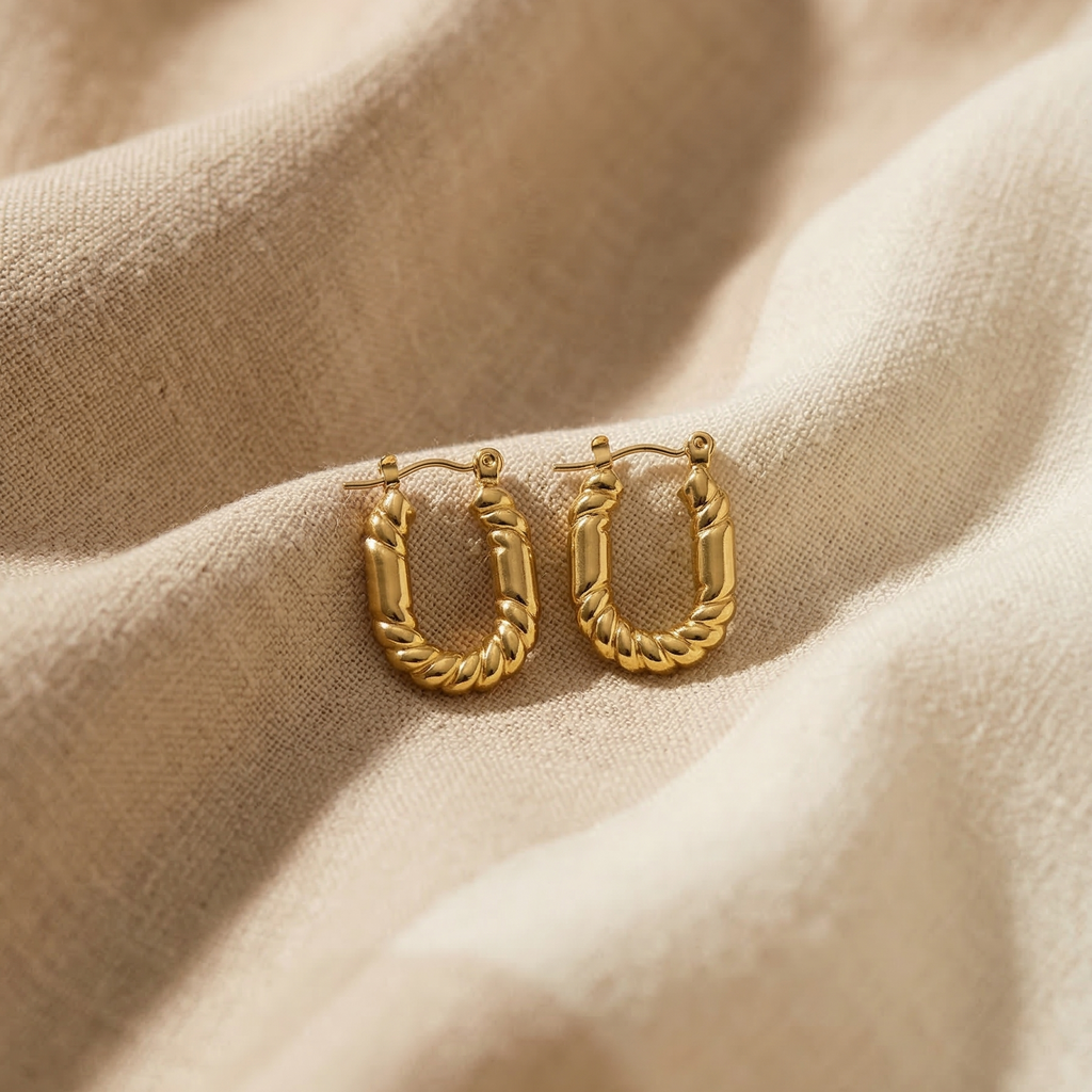 Gold hoop earrings on a beige fabric background