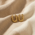 Gold hoop earrings on a beige fabric background