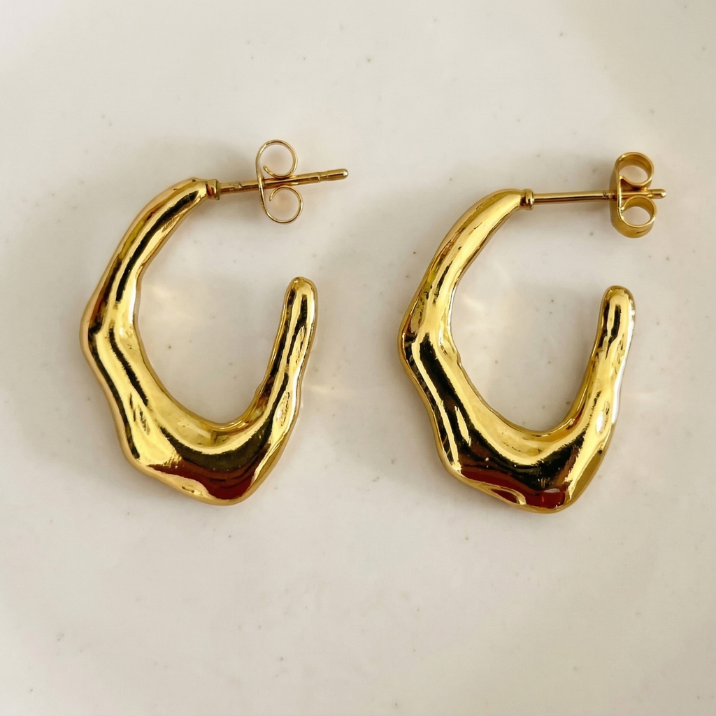 Gold hoop earrings on a light beige background