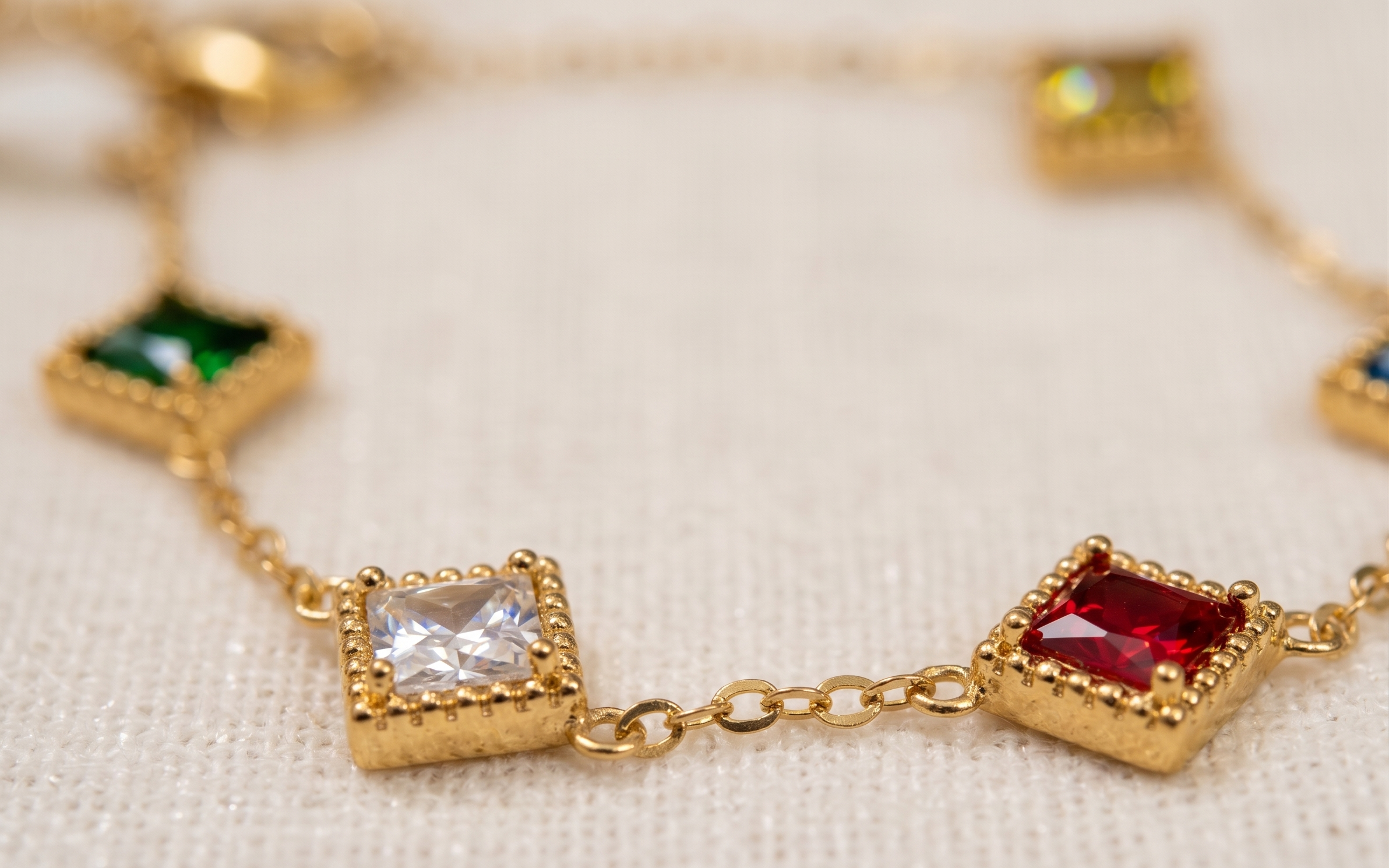 Gold bracelet with square gemstones on a light background