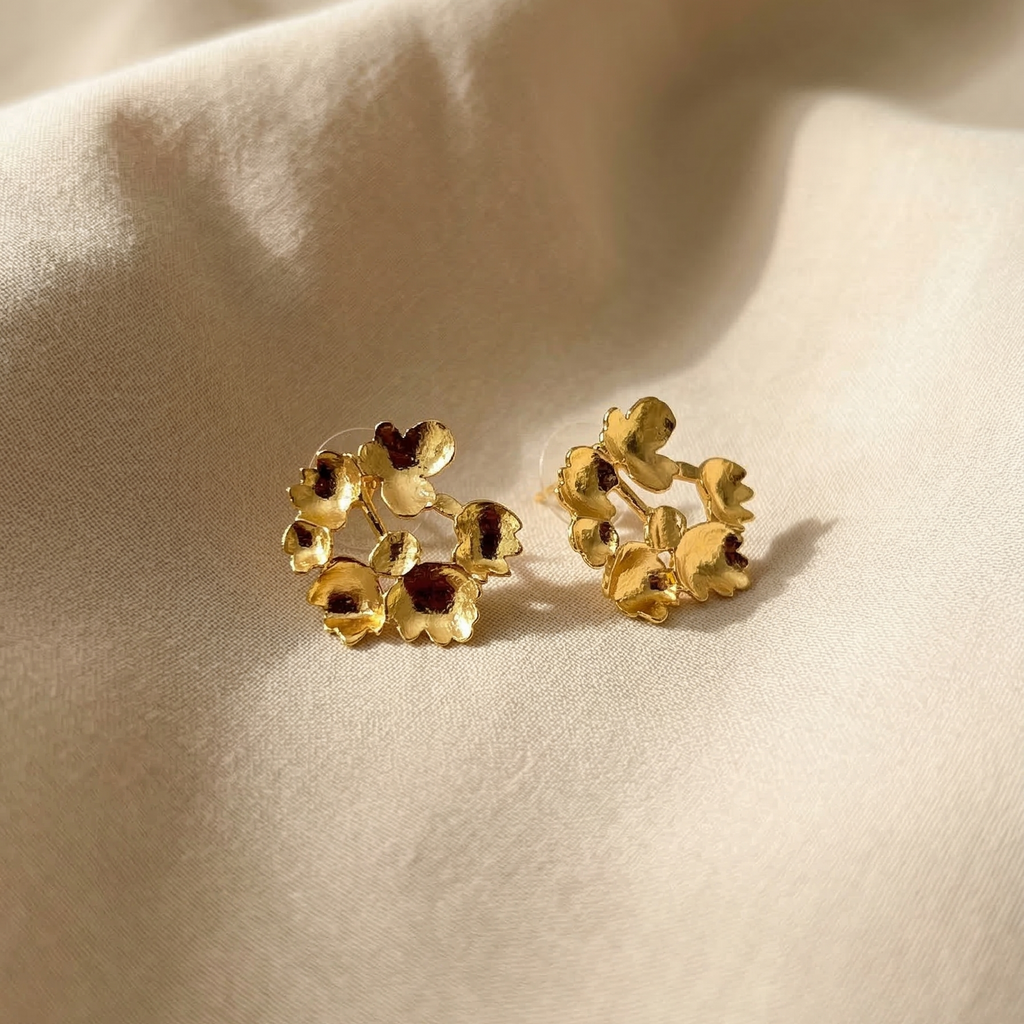 Gold floral earrings on a beige fabric background
