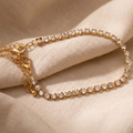 Gold bracelet with clear stones on a beige fabric background