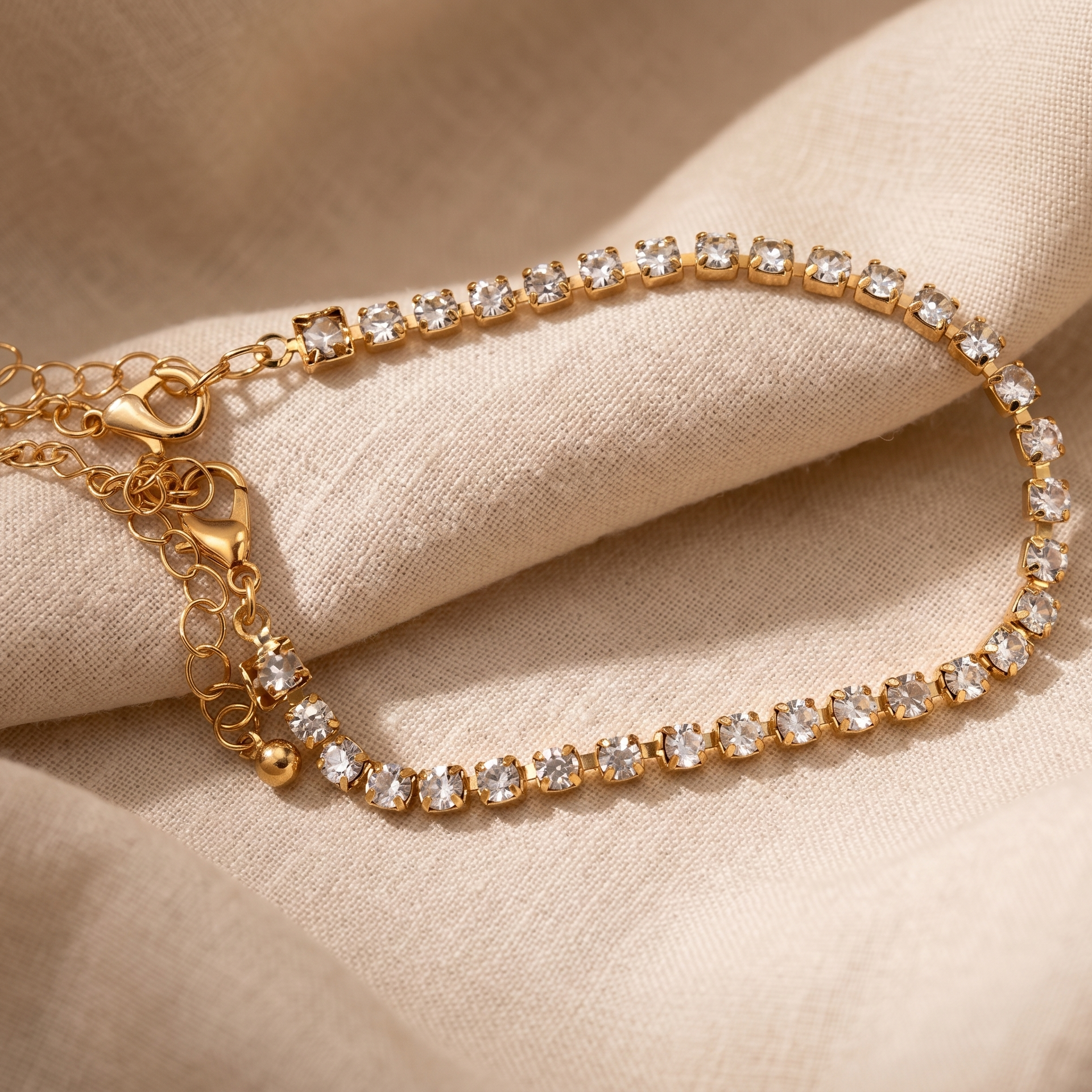 Gold bracelet with clear stones on a beige fabric background