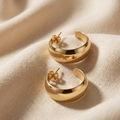 Gold hoop earrings on a beige fabric background
