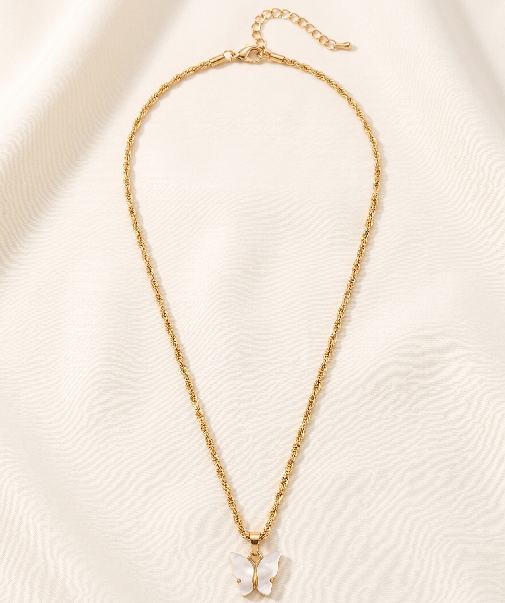 Gold necklace with a small pendant on a beige background