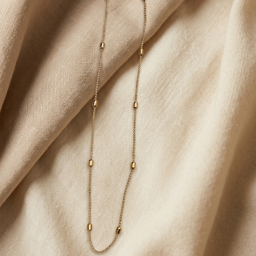 Gold necklace on a beige fabric background