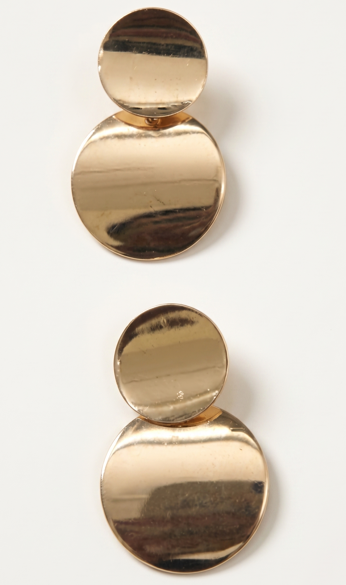 Gold circular earrings on a white background