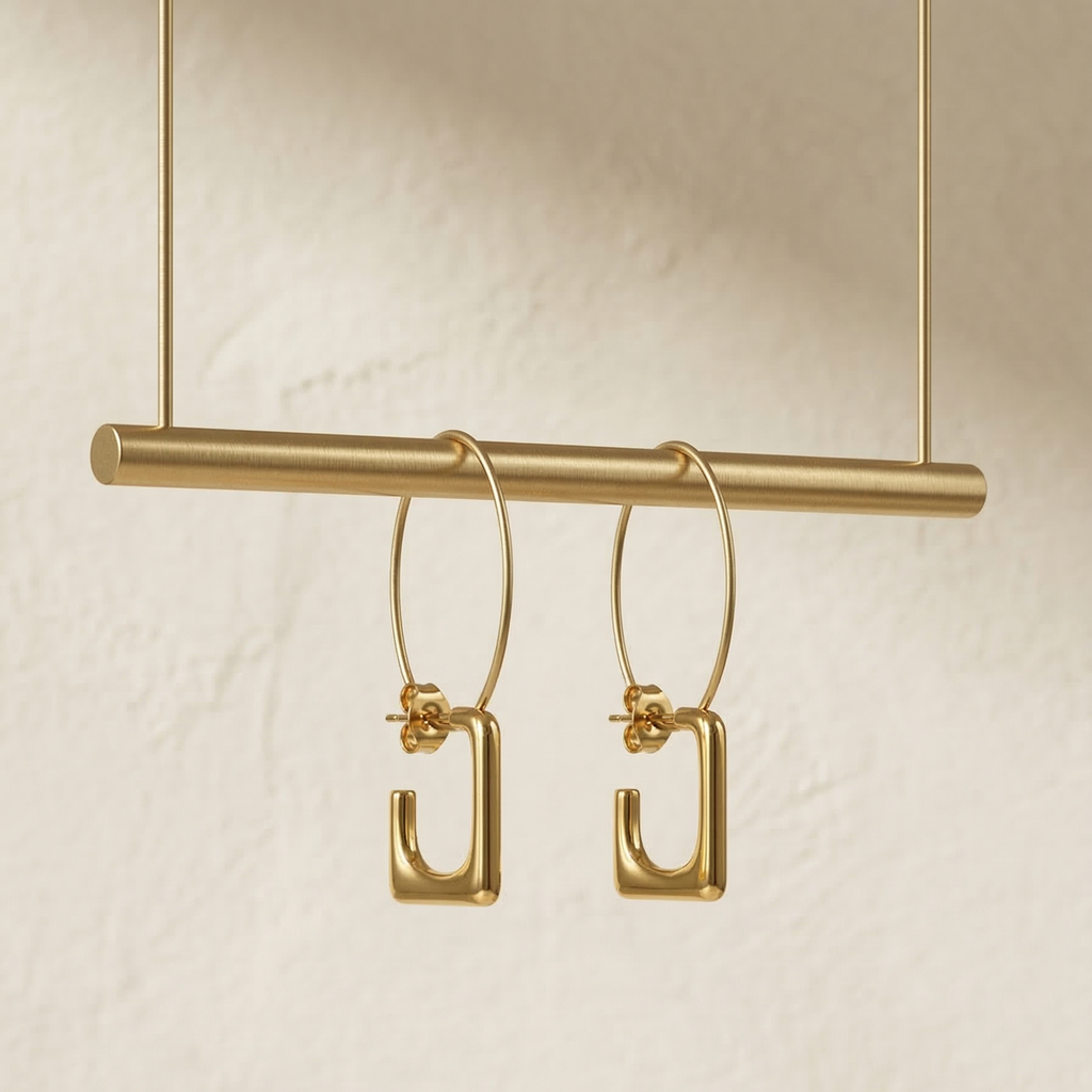 Gold hoop earrings on a gold bar against a beige background