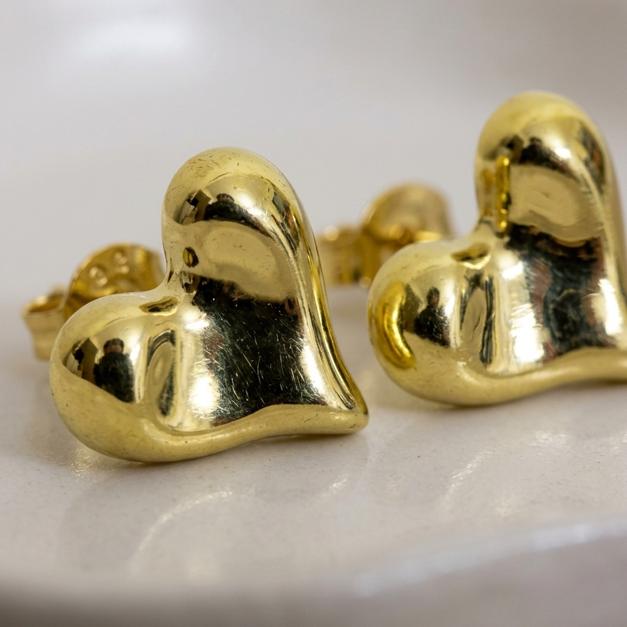 Gold heart-shaped earrings on a white background
