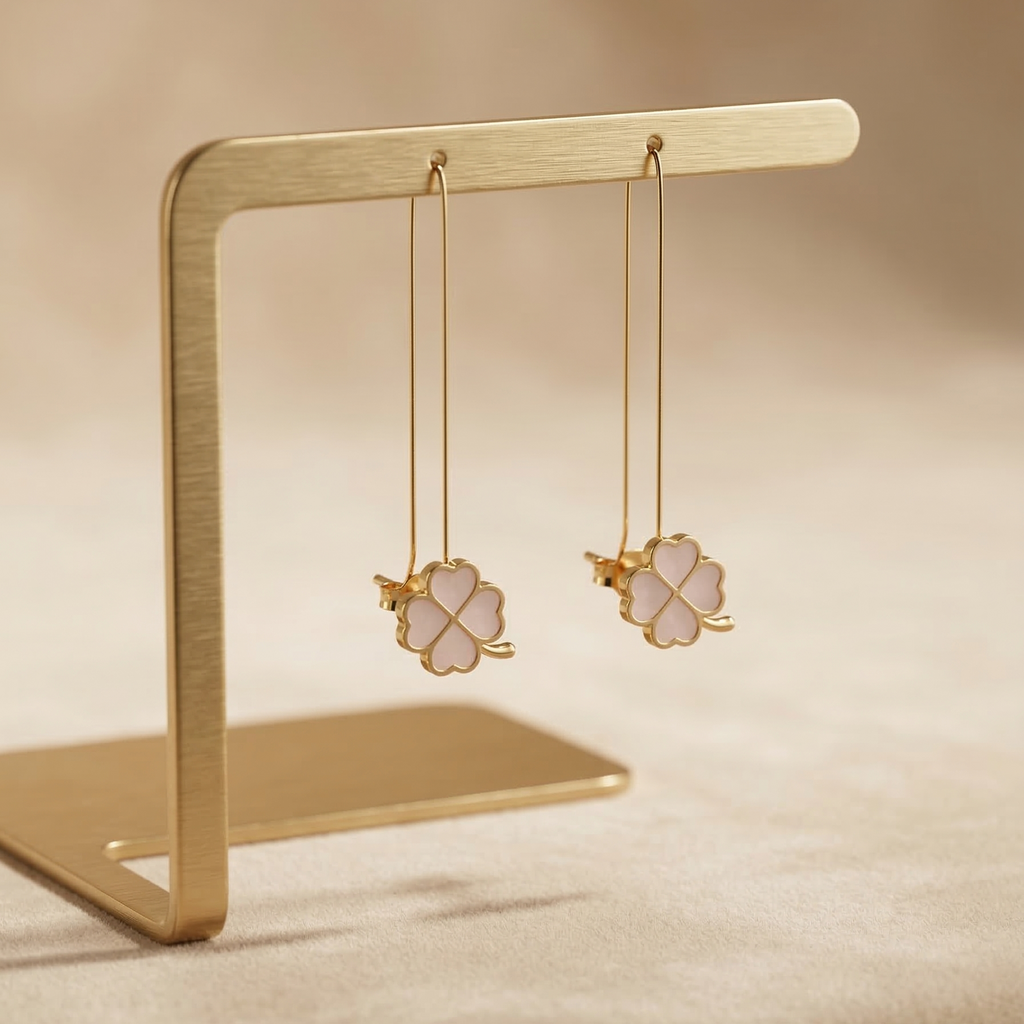 Gold earrings on a gold stand against a beige background