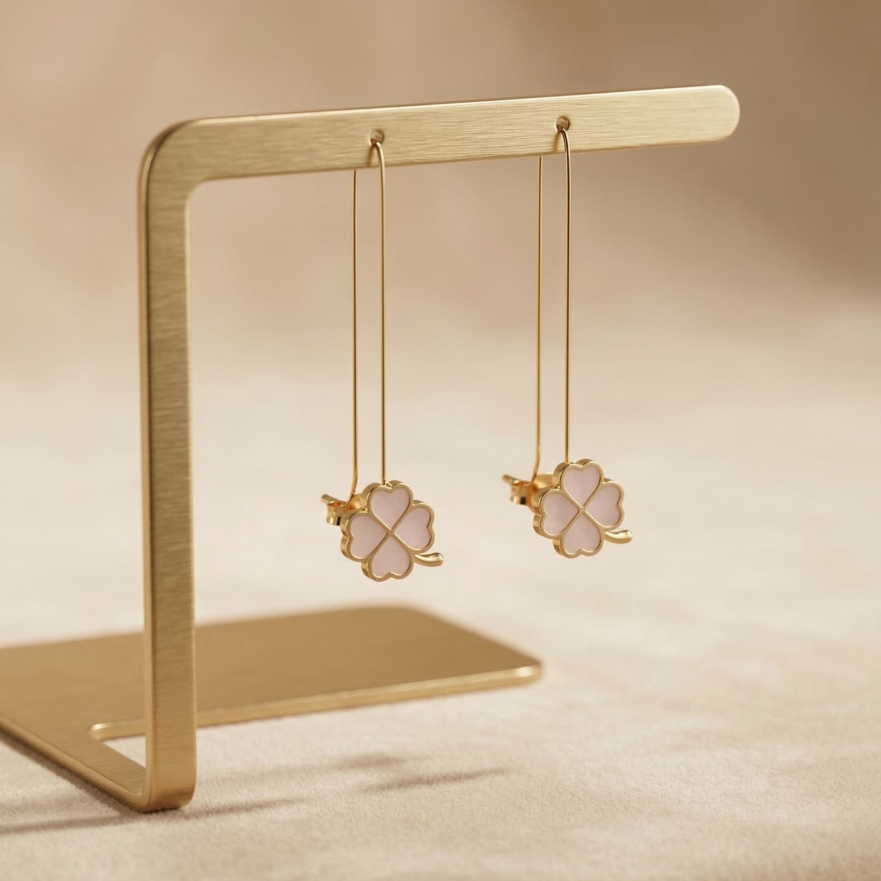 Gold earrings on a gold stand against a beige background