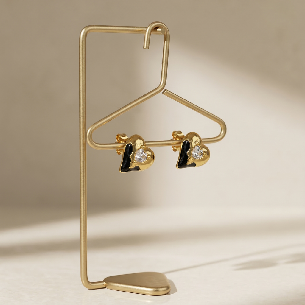 Gold earring stand with heart-shaped earrings on a beige background
