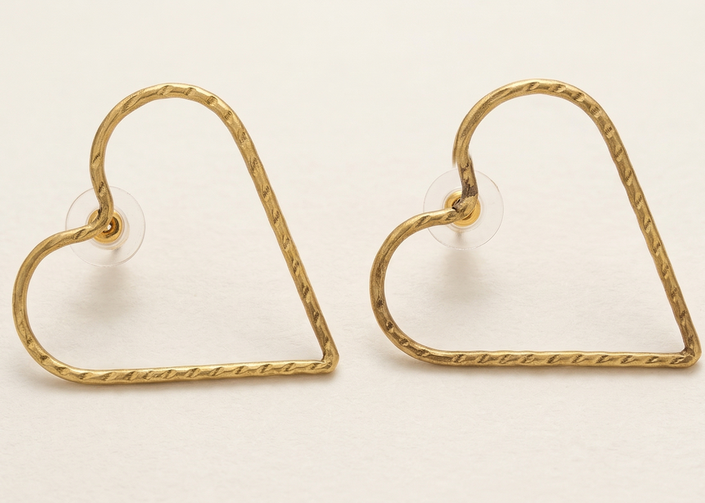 Gold heart-shaped earrings on a beige background