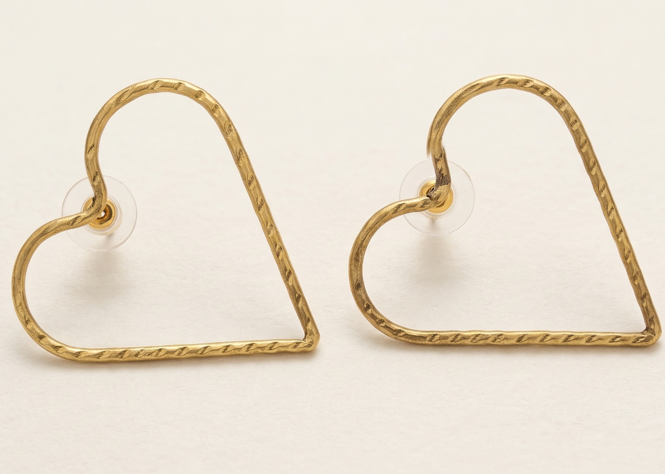 Gold heart-shaped earrings on a beige background