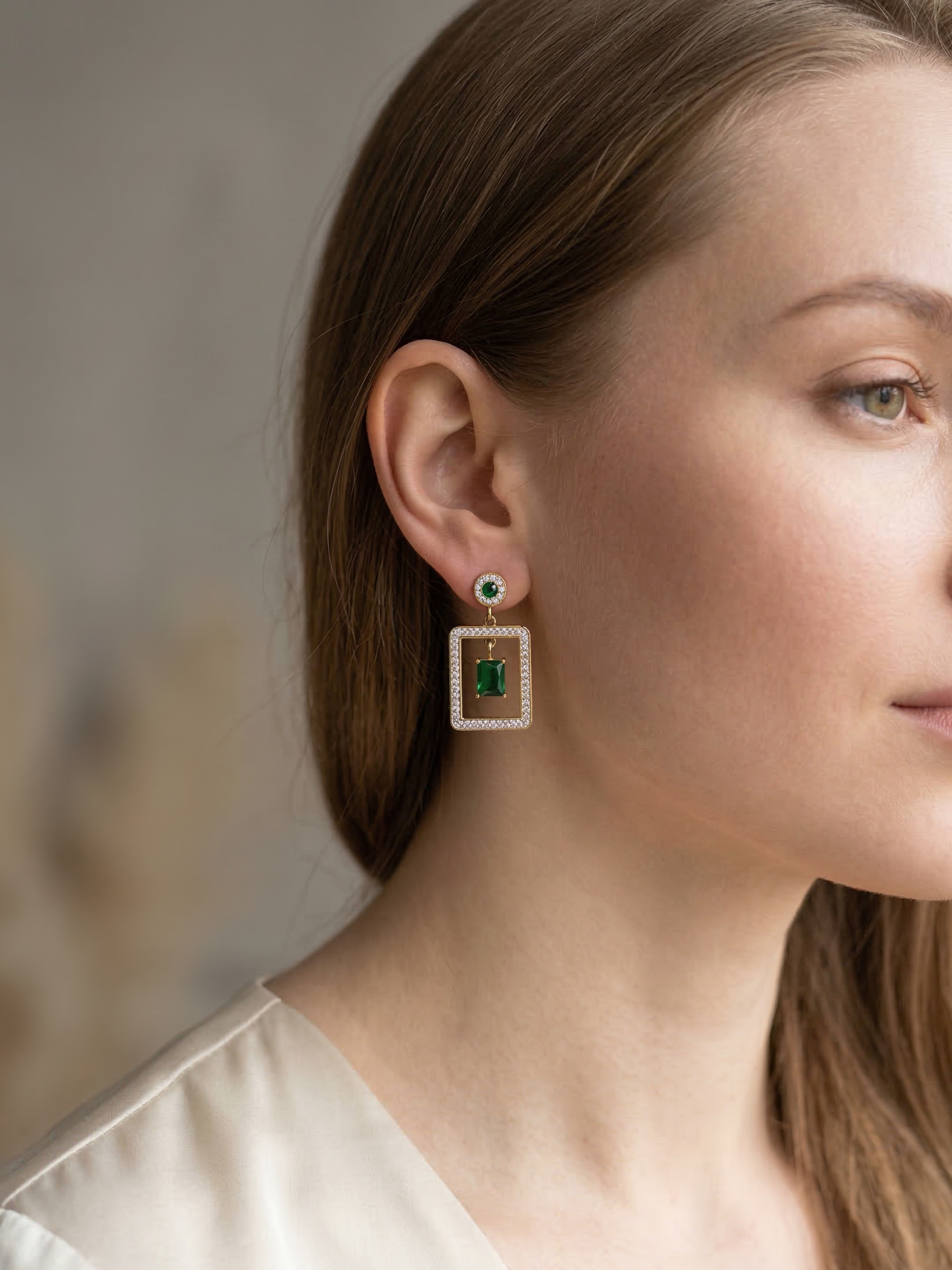 Close-up of a woman wearing a pair of earrings with a neutral background