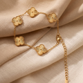 Gold bracelet with floral designs on a beige fabric background