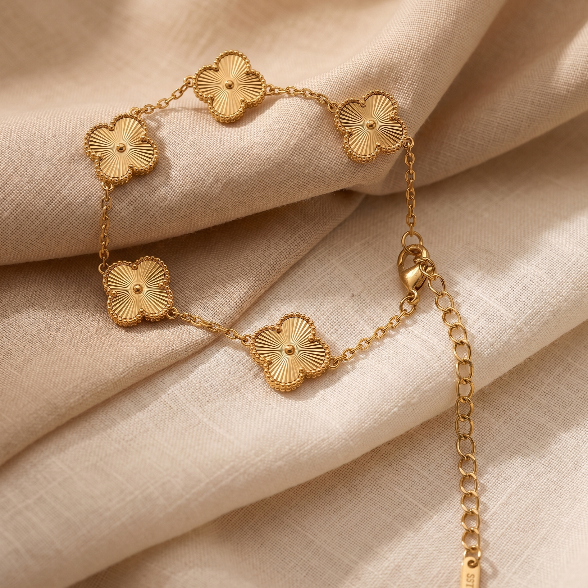 Gold bracelet with floral designs on a beige fabric background