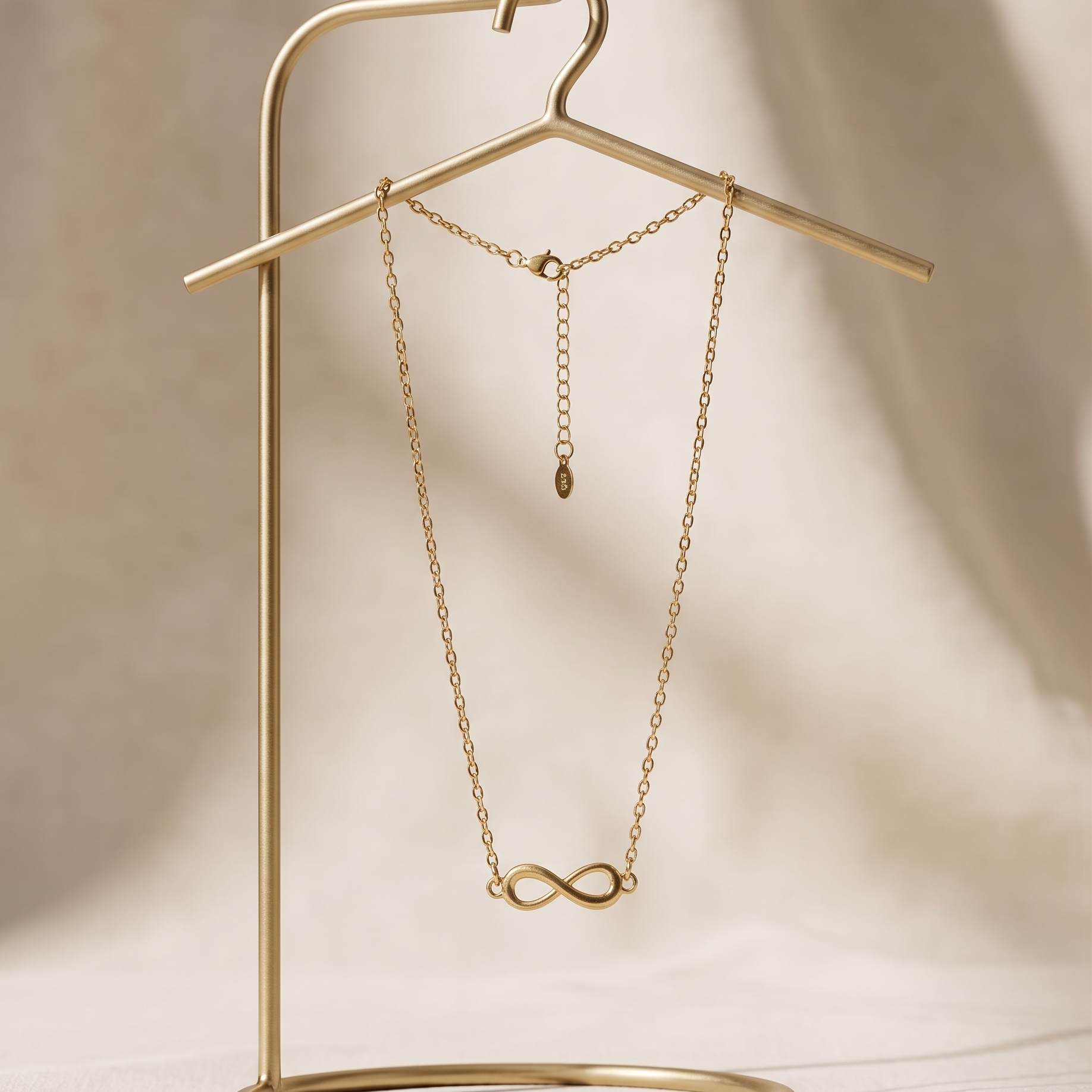 Gold necklace on a gold stand against a beige background