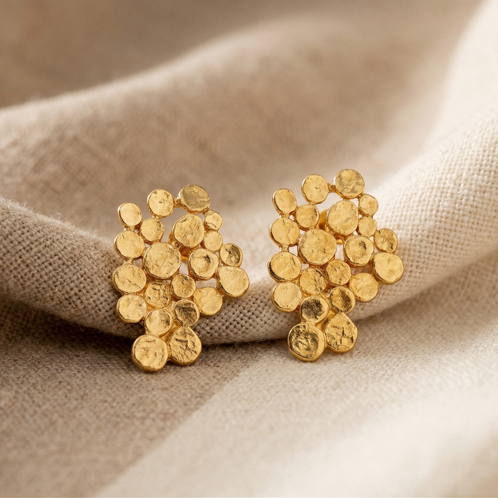Gold earrings on beige fabric