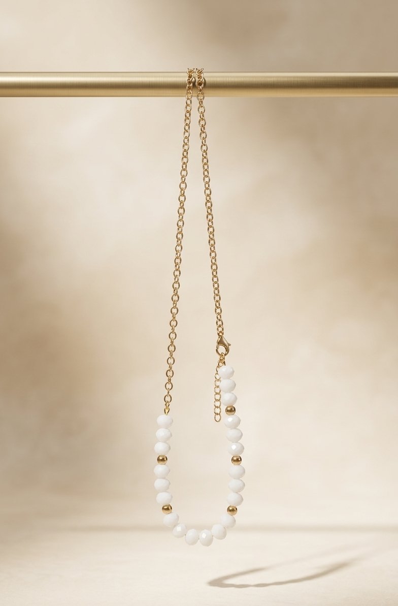 Gold and white beaded necklace on a beige background