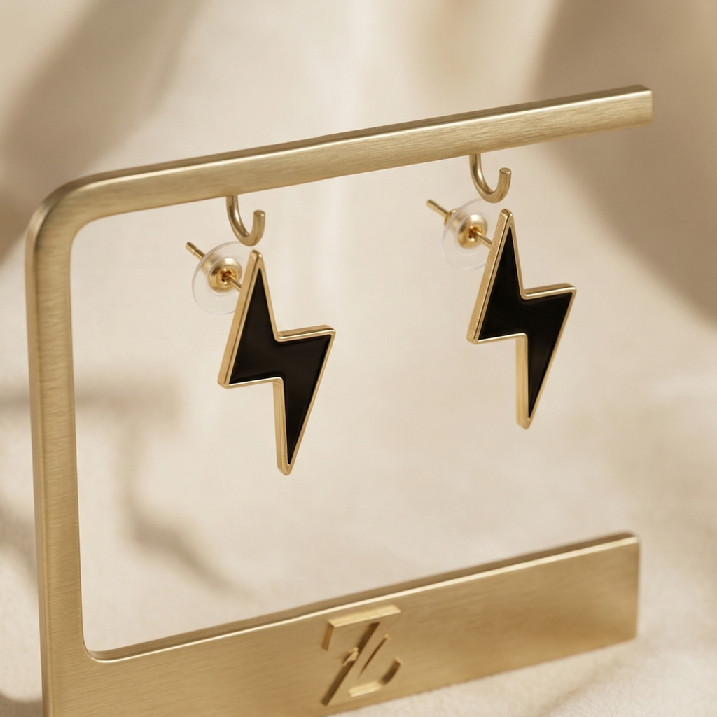Gold lightning bolt earrings on a gold stand with a soft beige background