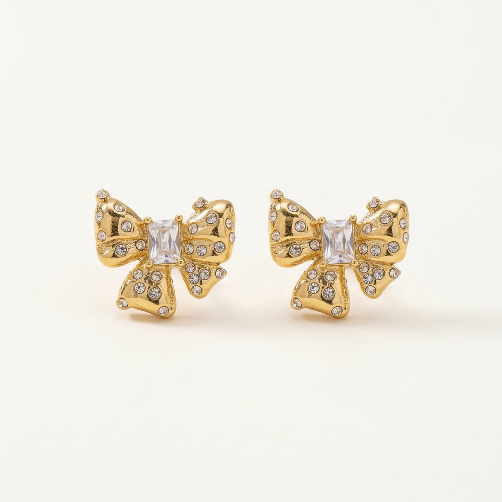 Gold butterfly earrings with clear gemstones on a light beige background