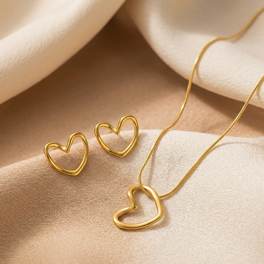 Gold heart-shaped jewelry set on a beige fabric background