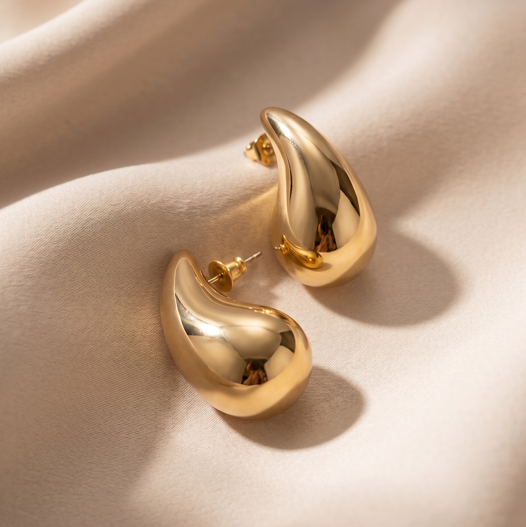 Gold hoop earrings on a beige fabric background