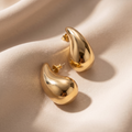 Gold hoop earrings on a beige fabric background
