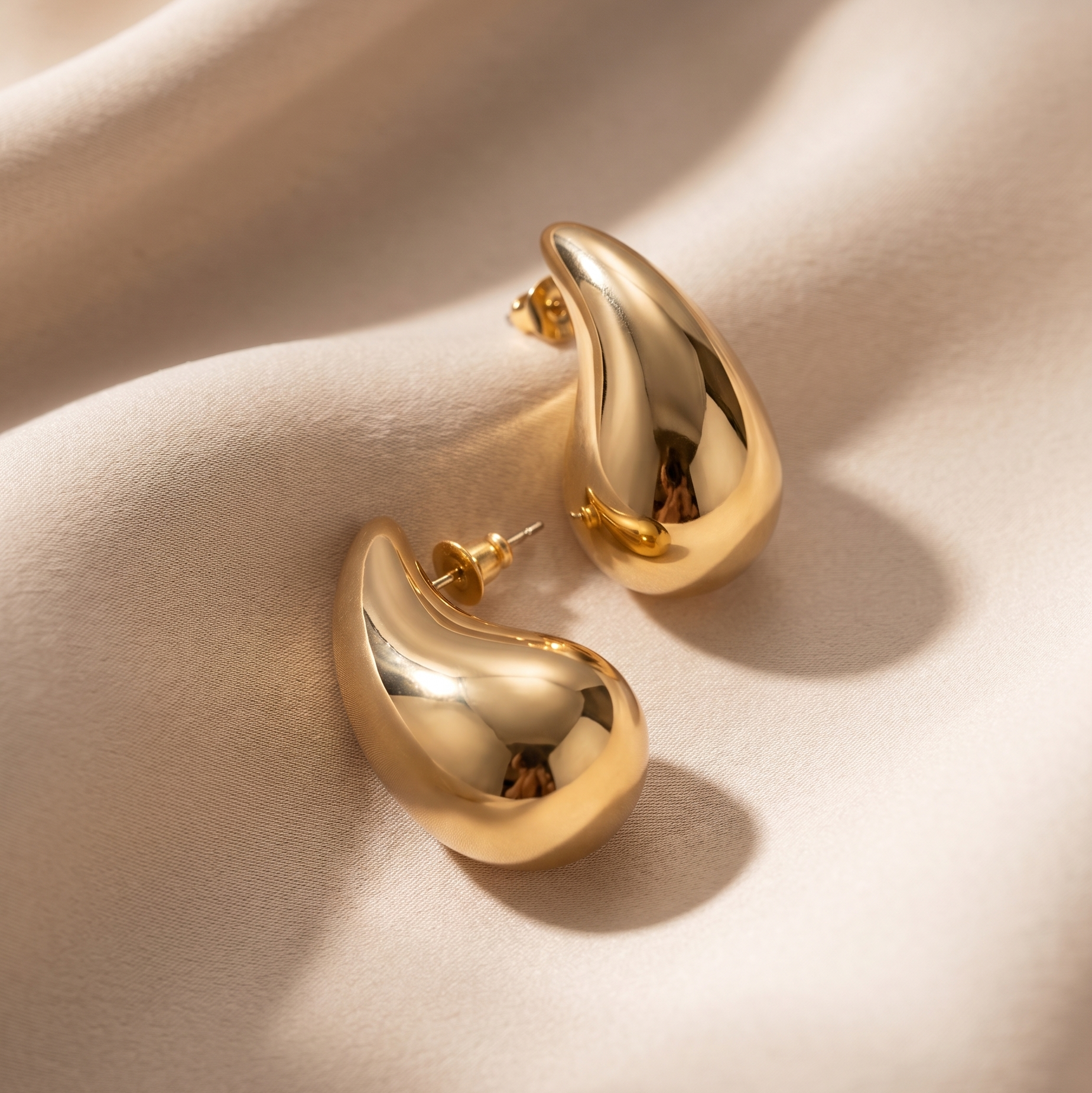 Gold hoop earrings on a beige fabric background