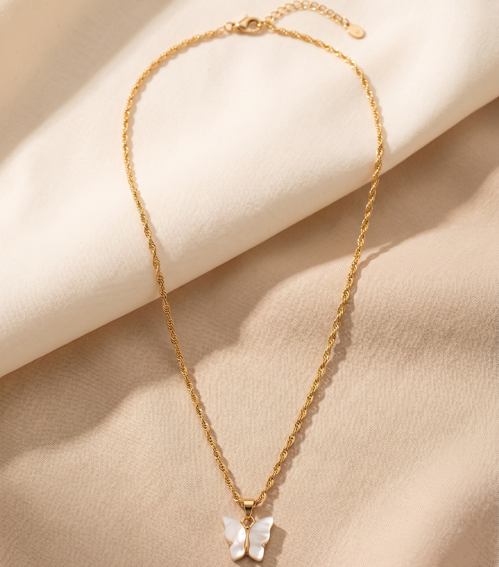 Gold necklace with a butterfly pendant on a beige fabric background