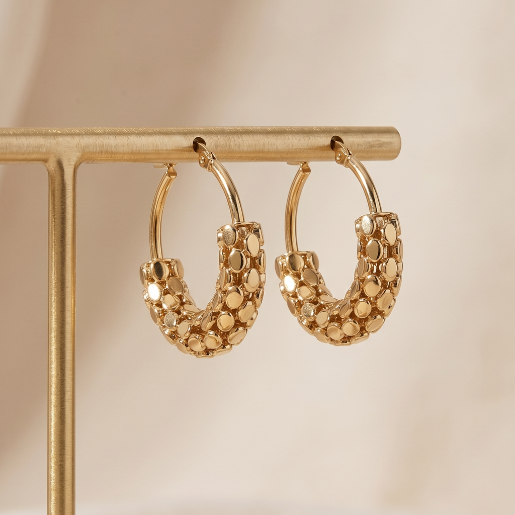 Gold hoop earrings on a gold stand with a soft beige background