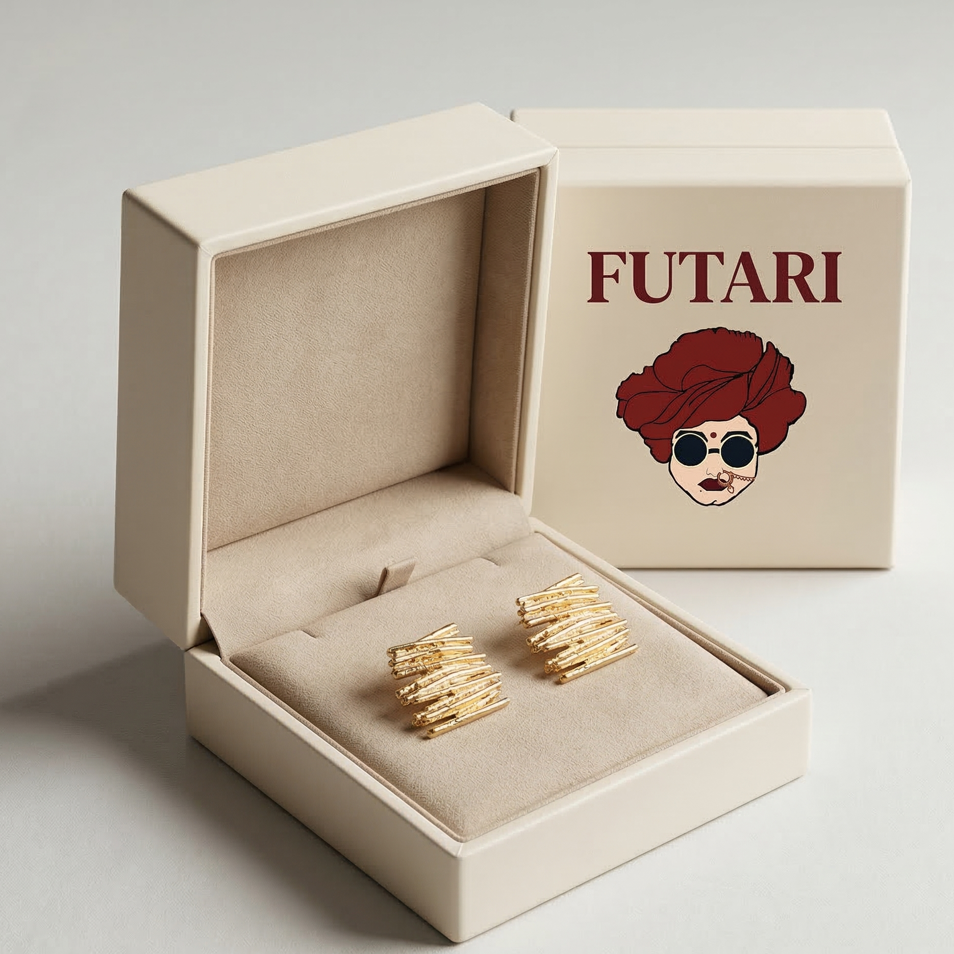 Gold earrings in an open beige box with 'FUTARI' branding on a light gray background
