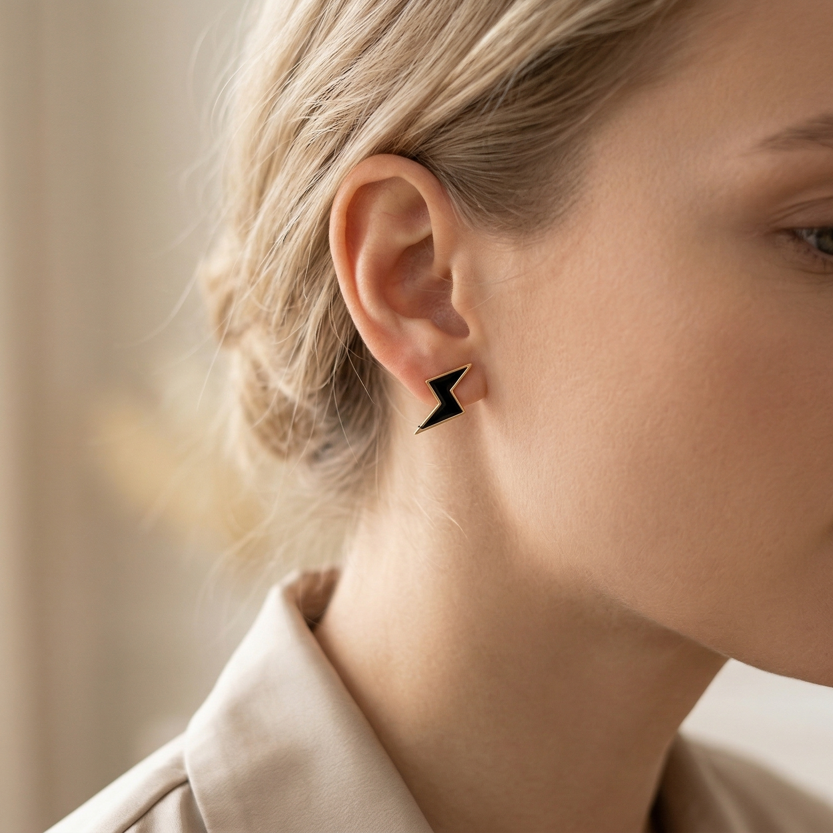 Close-up of a woman wearing a black geometric earring with a neutral background