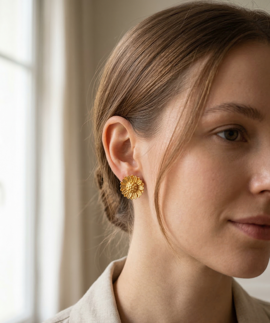 Woman wearing gold floral earrings with a neutral background
