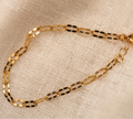 Gold chain bracelet on a beige fabric background