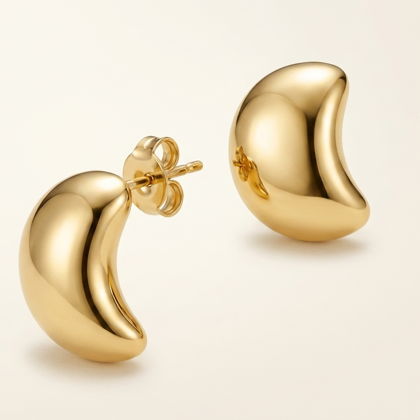 Gold crescent moon-shaped earrings on a beige background
