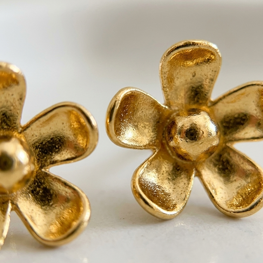 Gold flower-shaped earrings on a light background