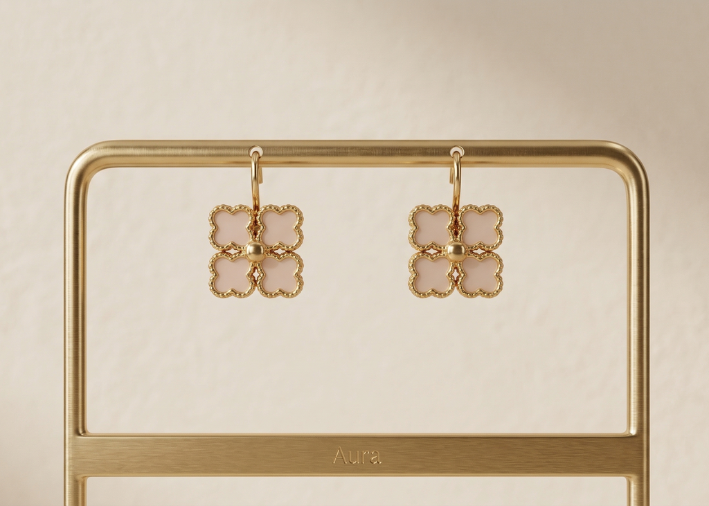 Pair of gold earrings on a gold stand with a beige background